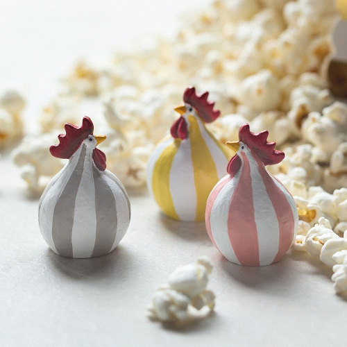 Drei gestreifte Nääsgränsgården Osterhühner (gelb, rosa, grau) der Serie Polka in einer Schale mit Popcorn dekoriert.