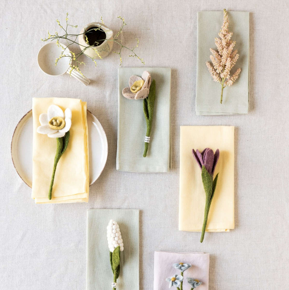 Filzblumen von Gry & Sif als nachhaltige Gastgeschenke und Tischdekoration auf Servietten – handgefertigt aus Wolle